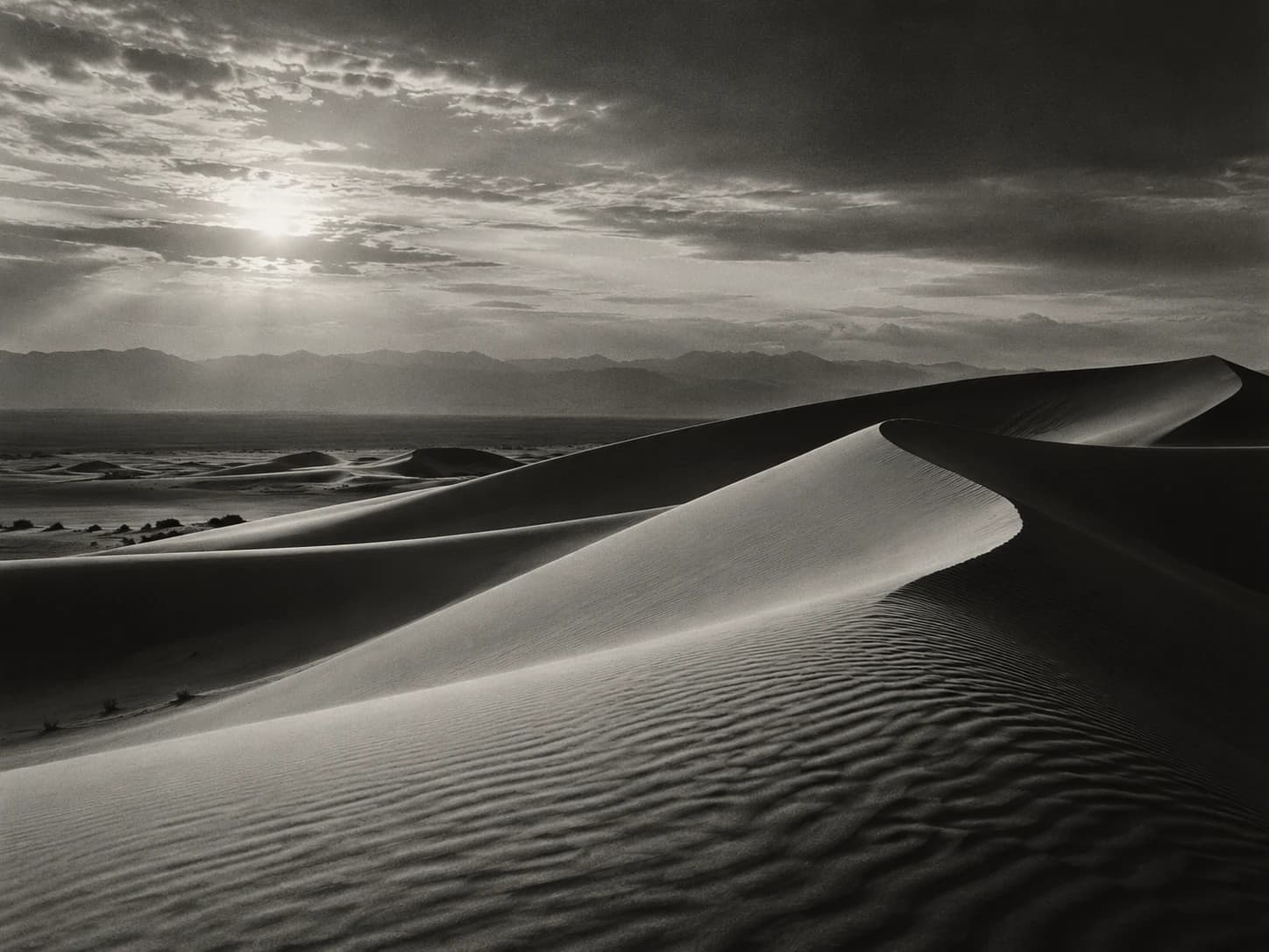 Monochrome desert dunes beneath dramatic clouds